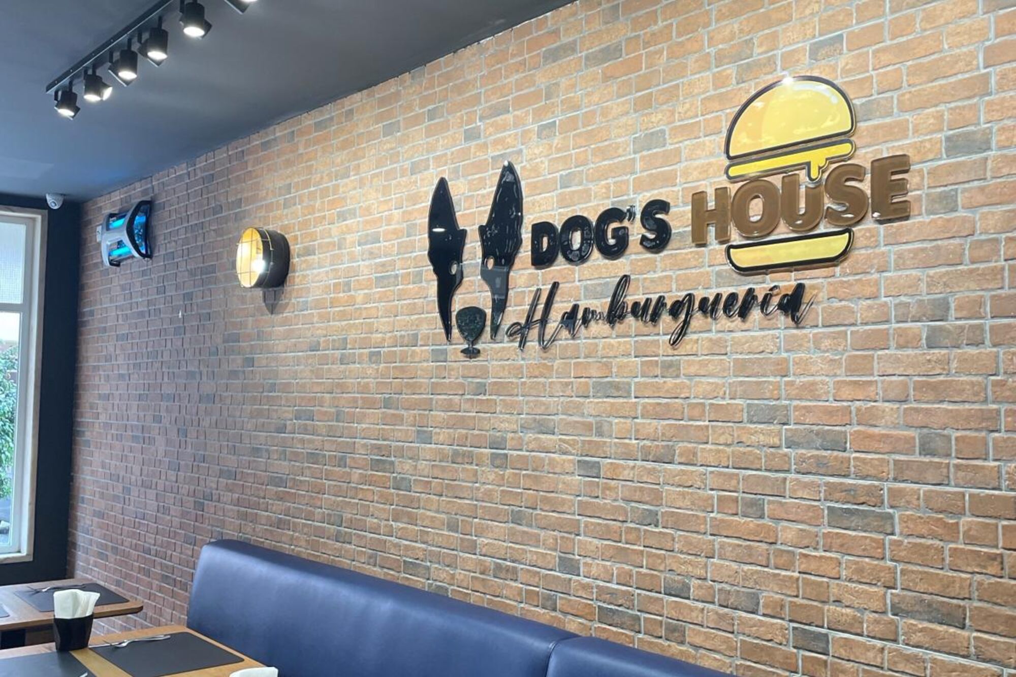 Interior da Dog's House Hamburgueria com parede de tijolo e o logótipo da casa